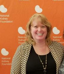 Maria standing in front of an orange National Kidney Foundation backdrop