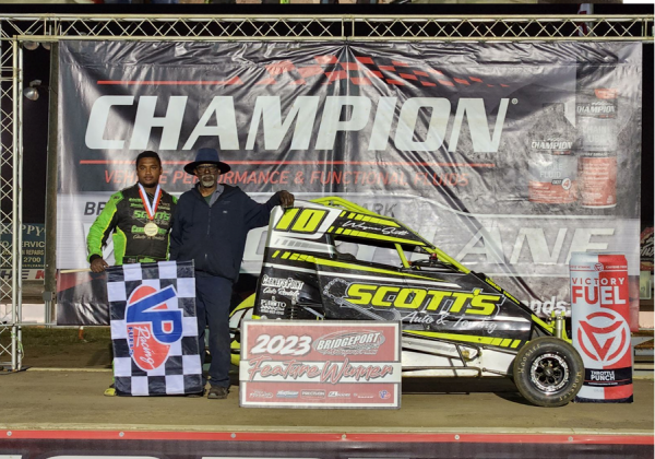 Wayne Scott (grandson, left) poses with his grandfather, Wayne Scott, after winning a race. The car features the grandfather's auto business, Scott's Auto & Towing.