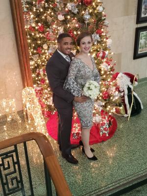 Cliff and Sarah standing in front of a Christmas tree on their wedding day in December 2019