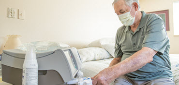 A DaVita home dialysis patient sets up his peritoneal dialysis machine at home. 